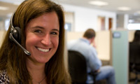 A smiling Disney Vacation Club Cast Member helps a Guest on the phone